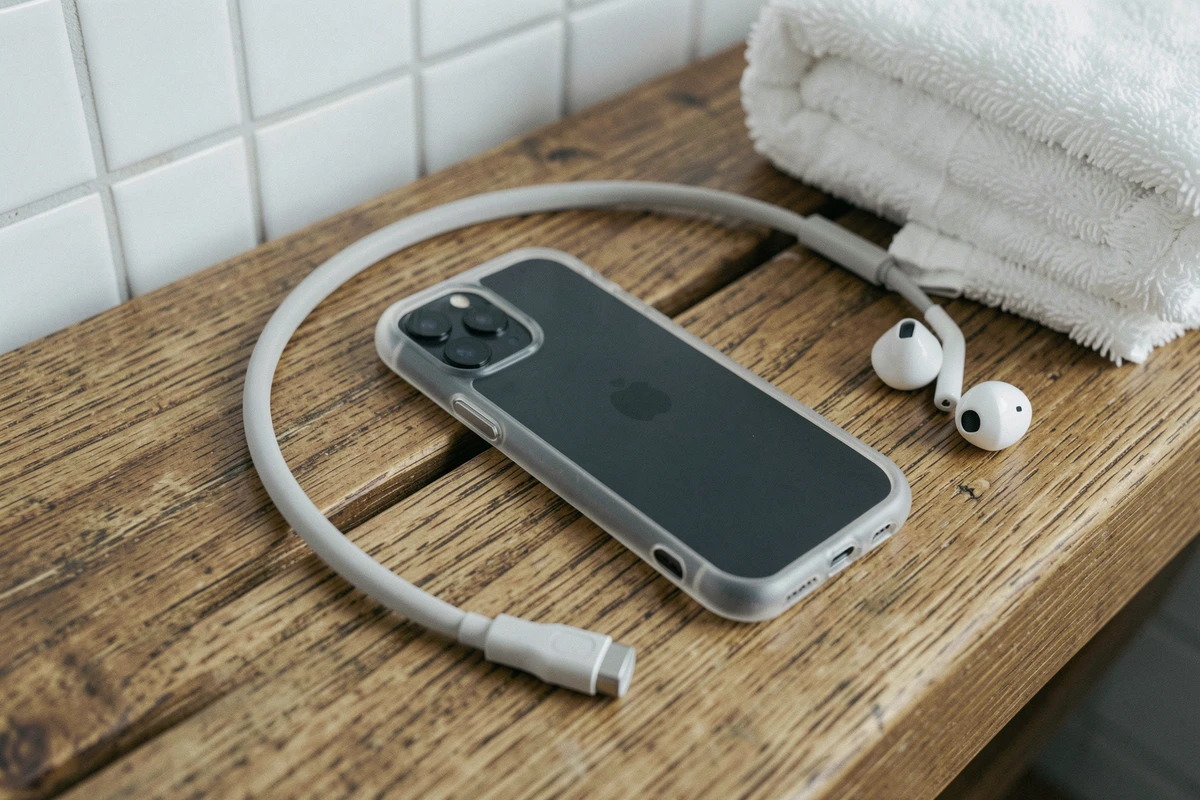 Gros plan d'une coque de téléphone sport transparente avec cordon en silicone sur un banc de vestiaire en bois