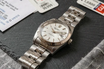Rolex Datejust 36 posée sur une surface en ardoise avec étiquettes de prix et catalogue de vente en arrière-plan